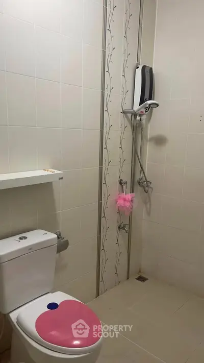 Modern bathroom with shower and toilet featuring a pink seat cover, ideal for compact spaces.
