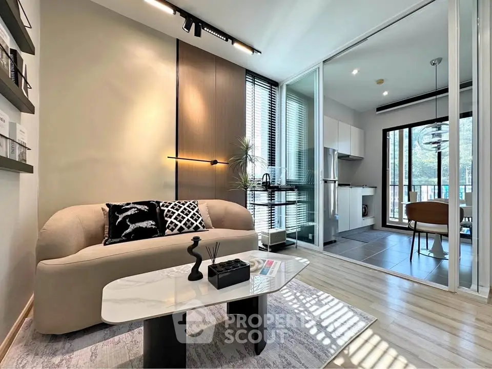 Modern living room with elegant decor and open kitchen layout, featuring sleek furniture and large windows.