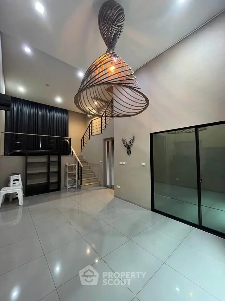 Modern interior with unique spiral chandelier and high ceiling in spacious living area.