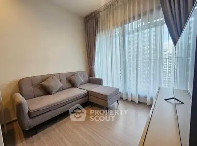 Modern living room with stylish sofa and large windows offering city views.