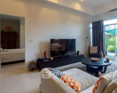 Spacious living room with modern decor and garden view, featuring a large TV and cozy seating area.