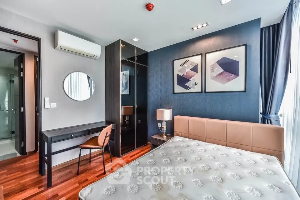 Modern bedroom with stylish decor, featuring a comfortable bed, elegant artwork, and a sleek vanity desk.