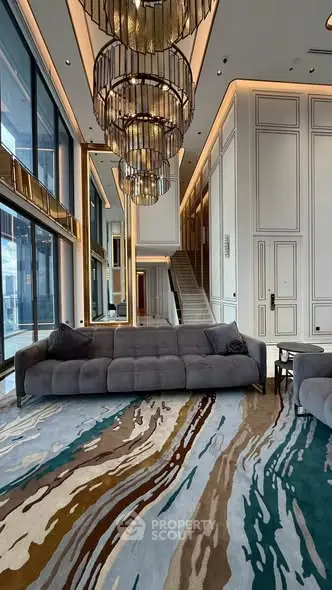 Luxurious modern living room with high ceilings, elegant chandeliers, and plush sofas in a sophisticated setting.