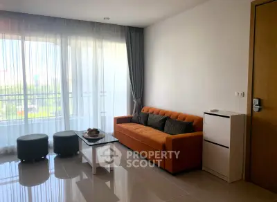 Modern living room with orange sofa and large window offering natural light and scenic view.