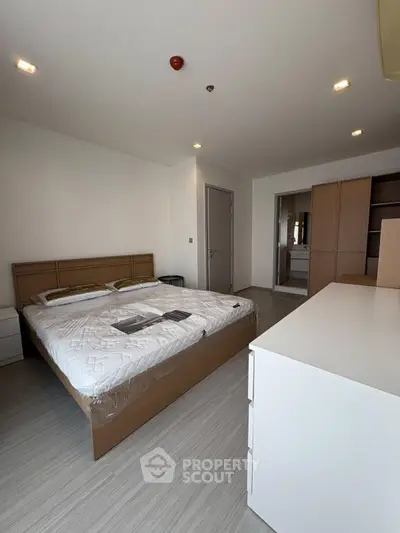 Spacious modern bedroom with sleek wooden furniture and ample natural light.