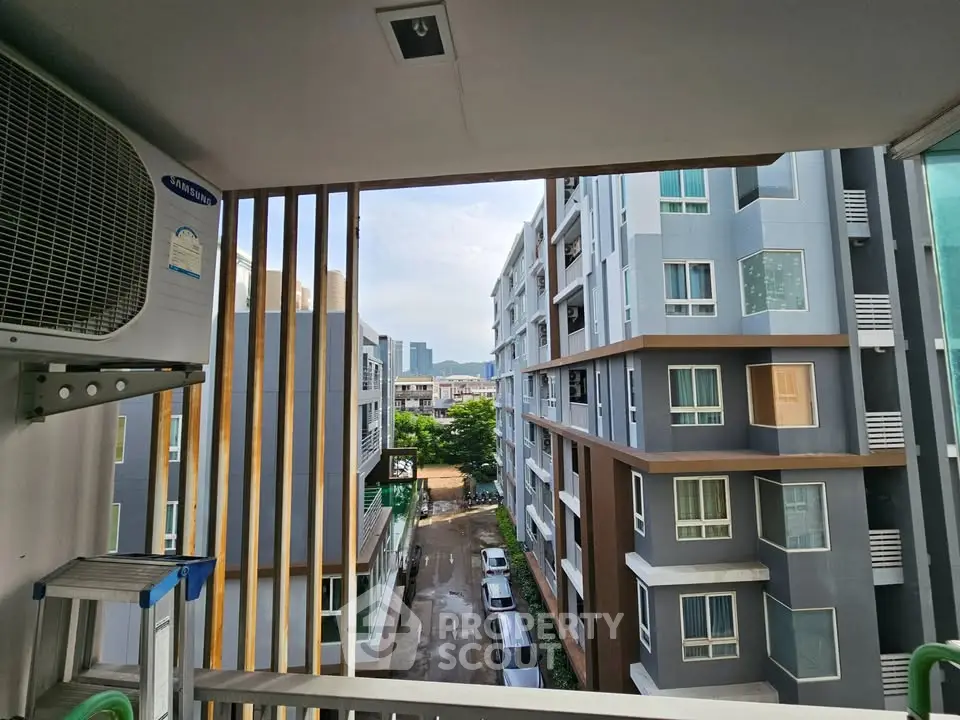 Modern urban apartment view with air conditioning unit and cityscape in the background.
