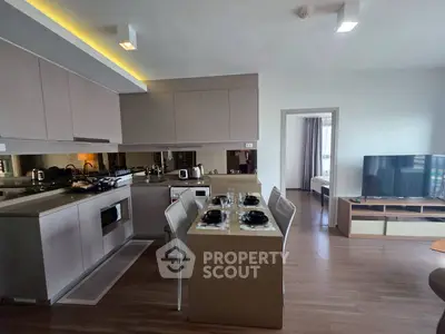 Modern open-layout kitchen with dining area and view into bedroom, featuring sleek cabinetry and appliances.