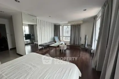 Spacious modern bedroom with large windows and stylish decor in a high-rise apartment.