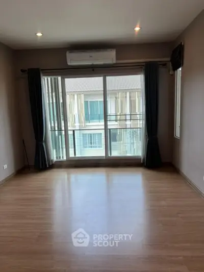 Spacious empty room with wooden flooring and large windows in modern apartment