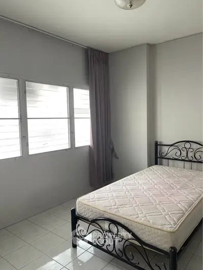 Bright bedroom with metal bed frame and large windows, perfect for cozy living.