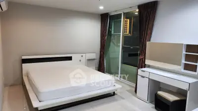 Modern bedroom with sleek furniture and city view balcony access.