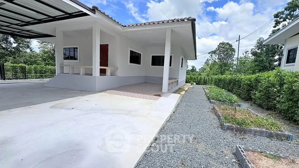 Charming single-story home with spacious driveway and lush greenery, perfect for serene living.