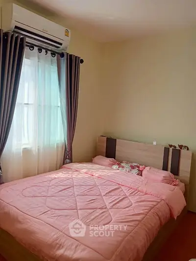 Cozy bedroom with pink bedding and natural light, perfect for relaxation.
