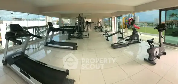 Spacious modern gym with panoramic windows and state-of-the-art equipment in luxury residential complex.