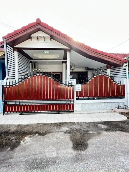 Charming single-story home with red roof and decorative gate, perfect for cozy living.