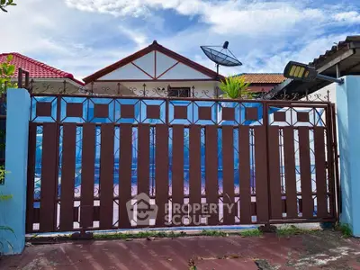 Charming residential property with decorative gate and satellite dish under a clear blue sky.