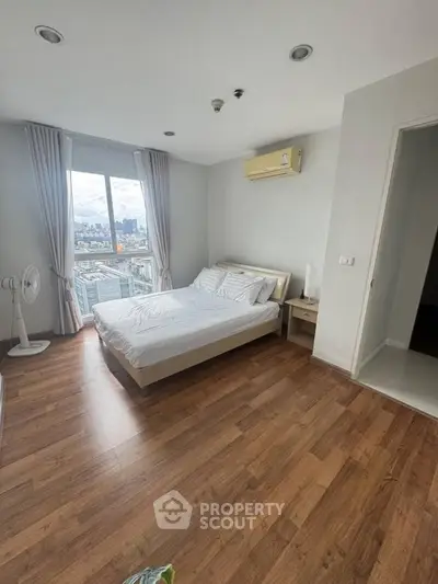 Spacious bedroom with city view and wooden flooring in modern apartment