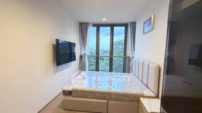 Modern bedroom with large window and wall-mounted TV, offering a serene view.