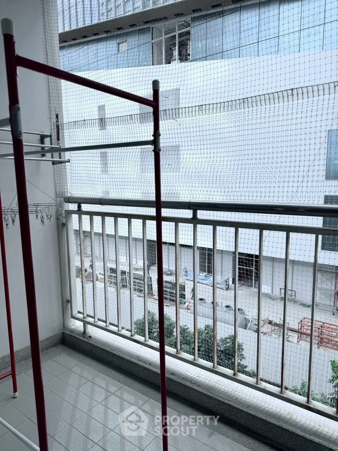 Spacious balcony with safety netting and urban view, ideal for relaxation and outdoor activities.