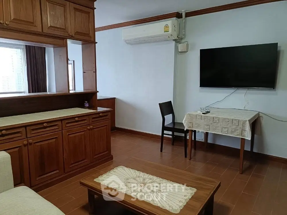Cozy living room with wooden furniture and wall-mounted TV, perfect for relaxation.