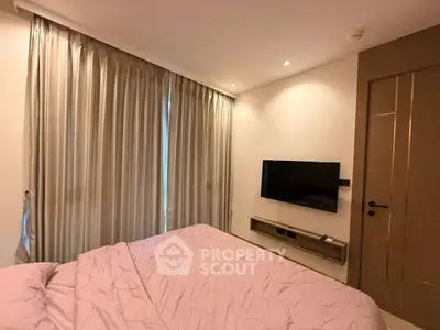 Cozy bedroom with modern decor and wall-mounted TV, perfect for relaxation.