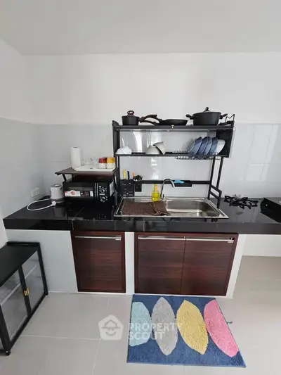Modern kitchen with sleek black countertop and gas stove, featuring open shelving and stylish cabinetry.