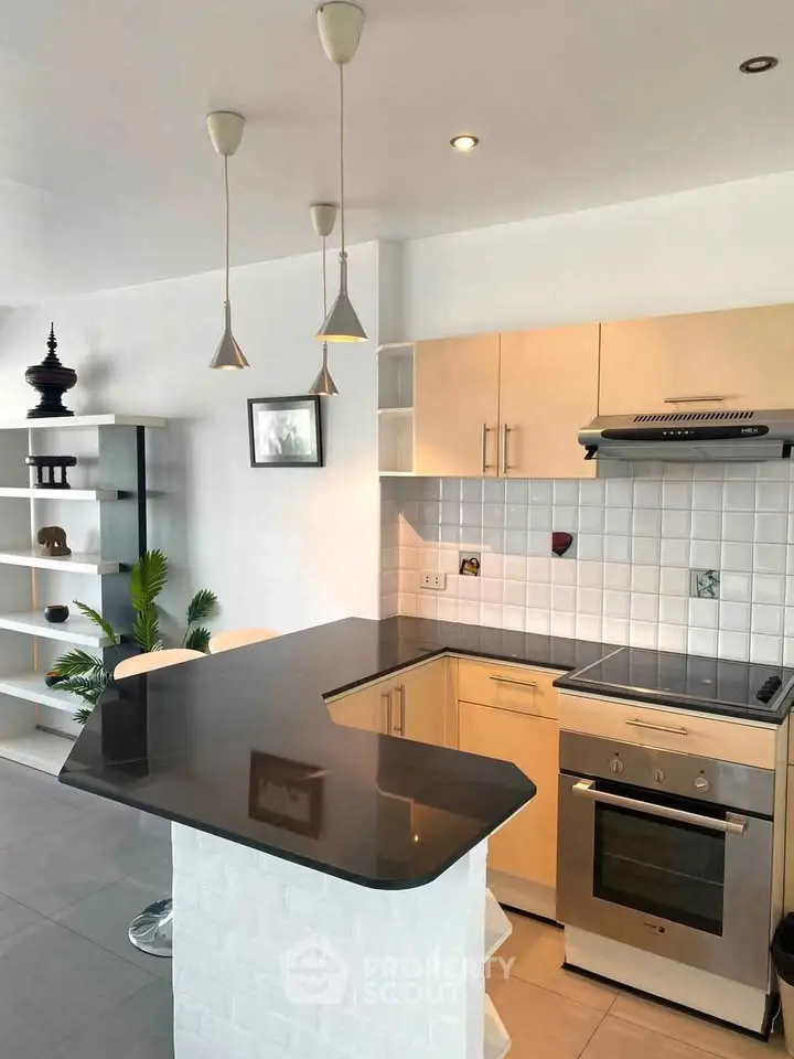 Modern kitchen with sleek black countertop and stainless steel appliances in a stylish apartment.