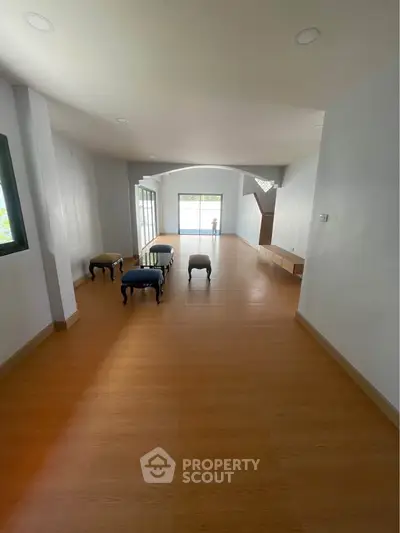 Spacious open-plan living area with wooden flooring and ample natural light.