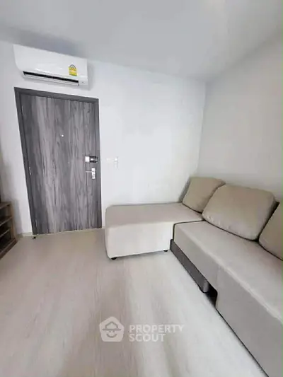 Modern living room with sleek gray sofa and air conditioning unit.