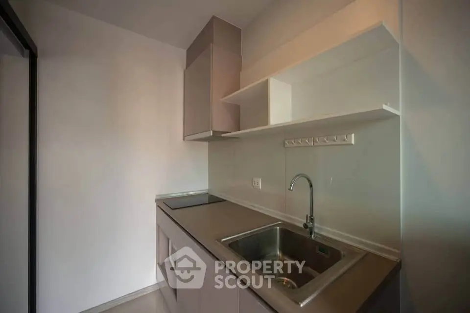 Modern minimalist kitchen with sleek cabinetry and stainless steel sink, perfect for compact living spaces.