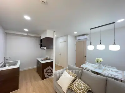 Modern open-layout kitchen and living room with stylish lighting and cozy decor.