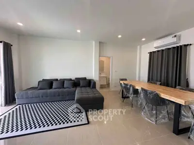Modern living room with stylish furniture and dining area, featuring sleek design and ample natural light.