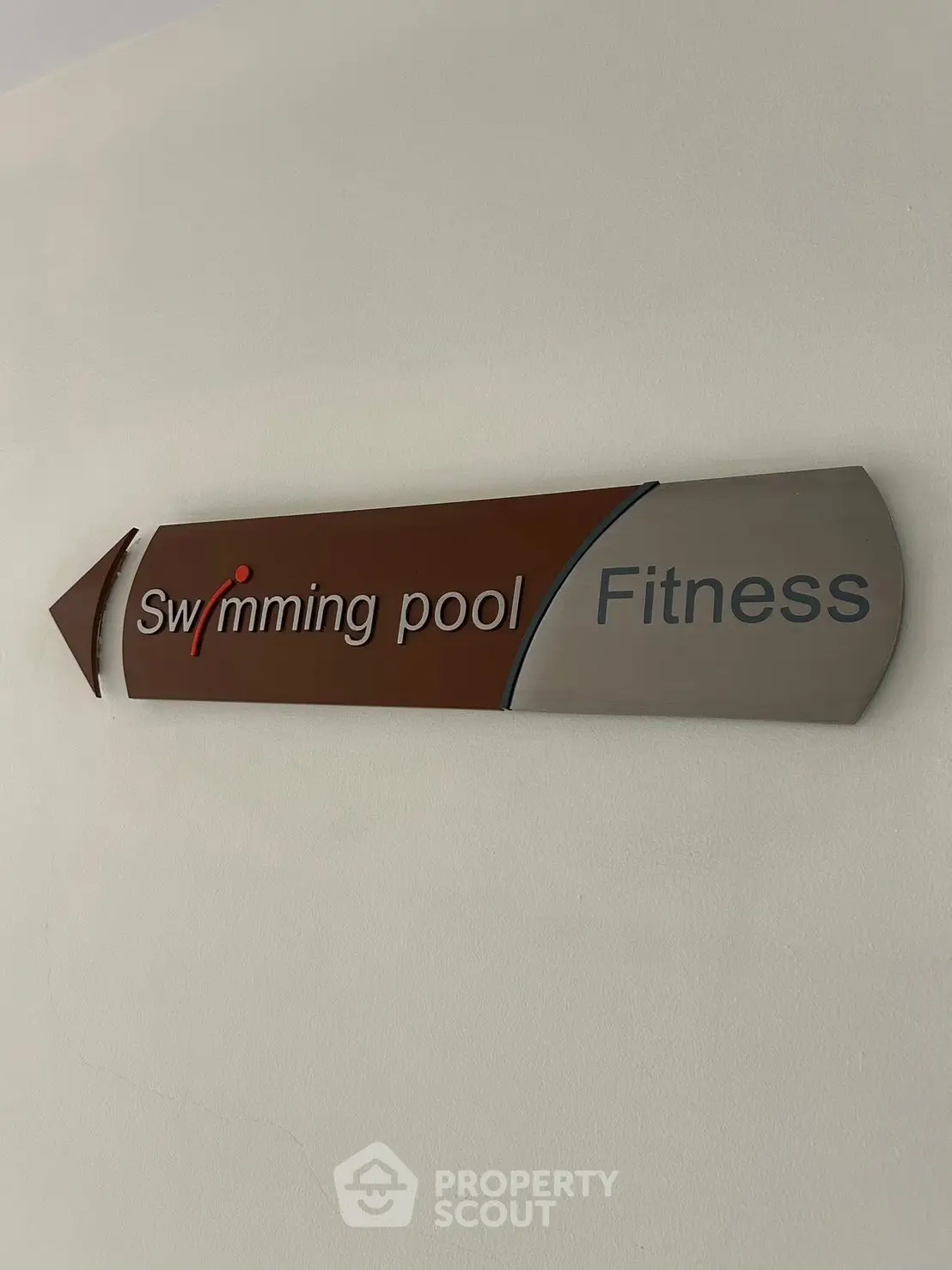 Directional sign for swimming pool and fitness area in a modern building.