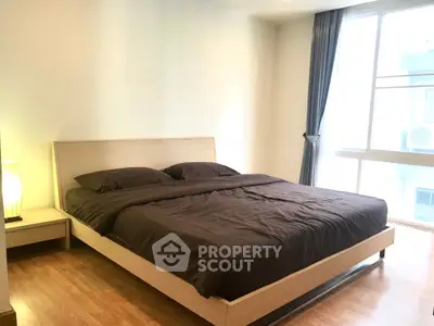 Spacious bedroom with large window and modern furnishings