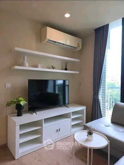 Modern living room with sleek TV unit and air conditioning, featuring natural light and stylish decor.
