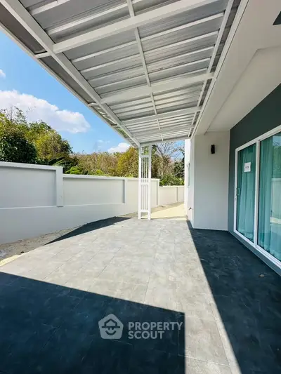 Spacious outdoor patio with modern roofing and sliding glass doors, perfect for relaxation and entertainment.