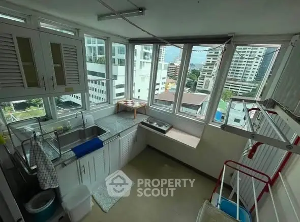Bright laundry room with large windows and city view, featuring modern cabinetry and ample counter space.