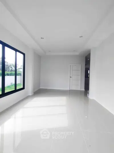 Spacious modern living room with large window and sleek tile flooring