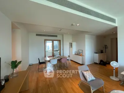 Spacious modern living room with wooden flooring and stylish furniture, featuring a dining area and large window view.
