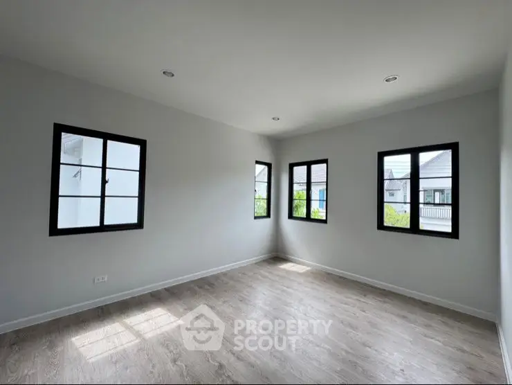 Spacious empty room with large windows and wooden flooring, perfect for customization.