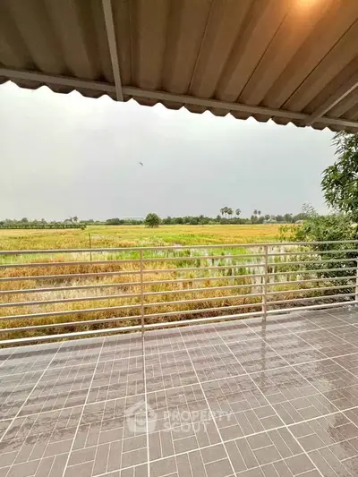 Scenic balcony view overlooking lush green fields and serene landscape.