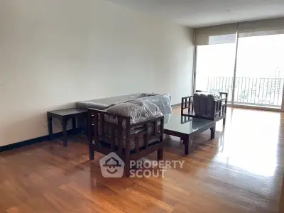 Spacious living room with wooden flooring and large windows offering city views.