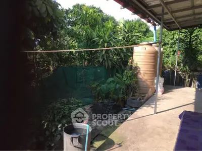Charming outdoor garden area with lush greenery and water storage tank, perfect for sustainable living.