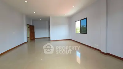 Spacious empty room with large window and glossy tiled floor