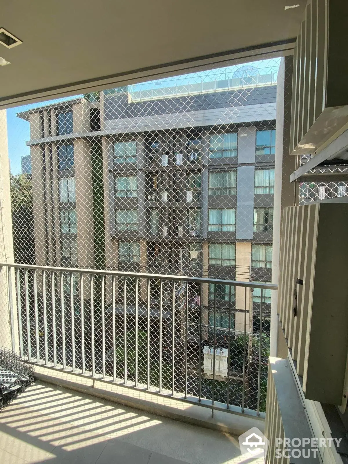 Modern balcony with safety net overlooking contemporary apartment building.