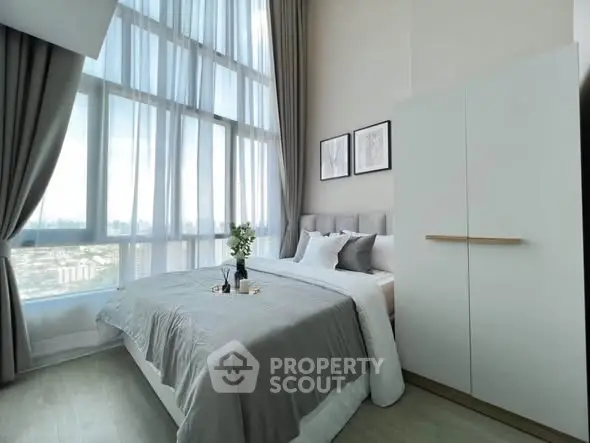Modern bedroom with large windows and stylish decor in high-rise apartment.
