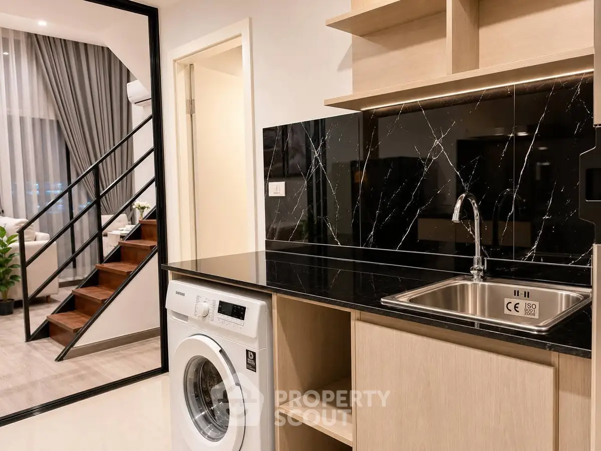 Modern kitchen with sleek black marble backsplash and washing machine in stylish apartment.
