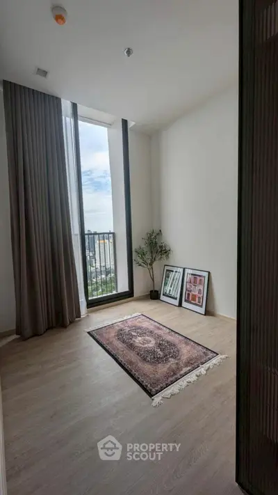 Bright room with large window and city view, featuring elegant decor and wooden flooring.