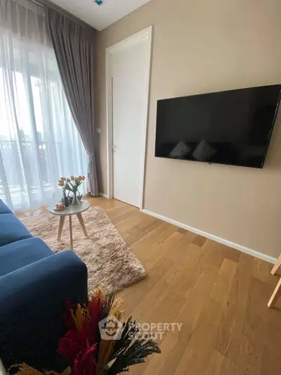 Modern living room with hardwood floors, large TV, and cozy decor