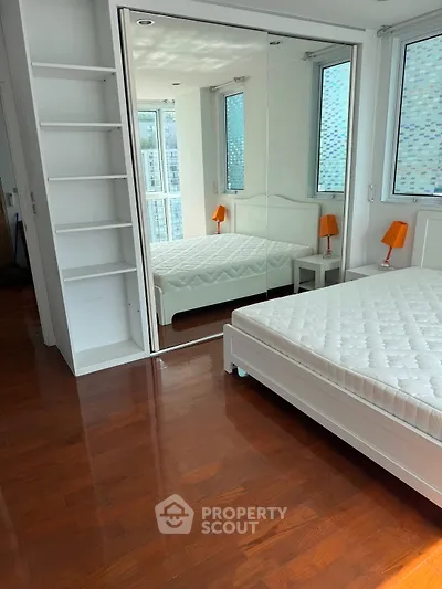 Bright bedroom with mirrored wardrobe and hardwood floors in modern apartment.
